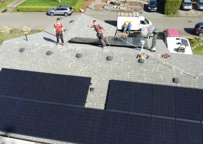 Image of solar installers on the roof waiving to the camera while they enjoy their workday